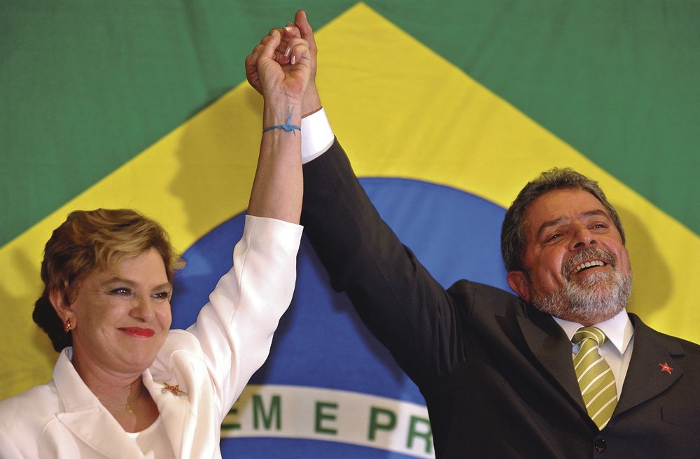 Brazilian president elect Luiz Inacio Lula da Silva raises his arms with his wife Marisa as he arrives to deliver a brief statement in Sao Paulo, Brazil on Sunday Oct. 27, 2002. The former union leader won Brazil's presidential election runoff by a landslide Sunday, marking a historic shift to the left for Latin America's largest country. (AP Photo/Dario Lopez-Mills)