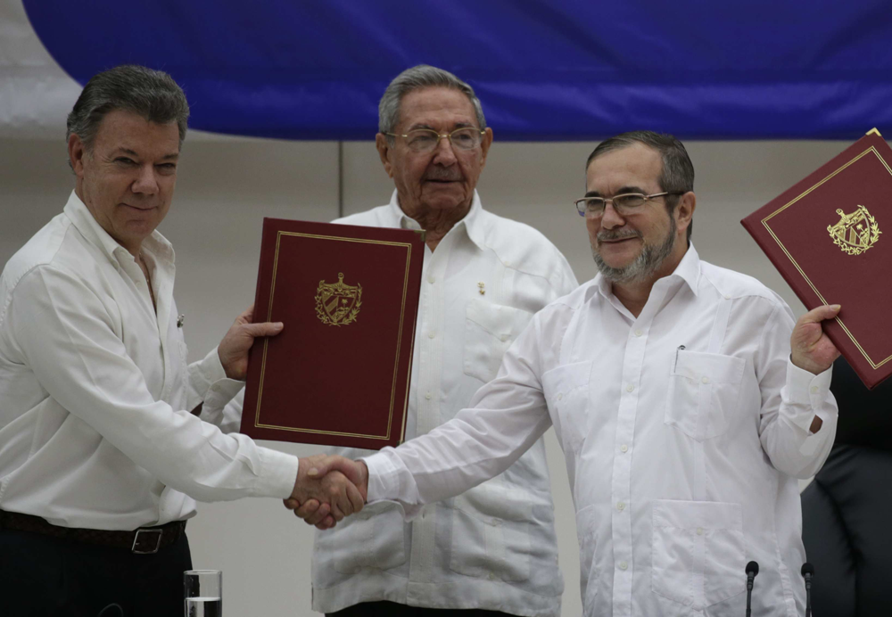 Colombias dåvarande president Juan Manuel Santos skakar hand med FARC-gerillans ledare Rodrigo Londoño Echeverri, även kallad ”Timosjenko”, medan Kubas president Raúl Castro ser på i Havanna 23 juni 2016. Foto: Hannah Foslien/AP/TT.