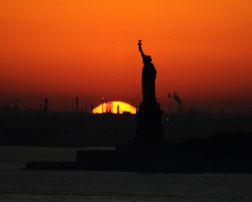 The sun sets behind the Statue of Liberty in New York, Sunday, Nov. 8, 2009. (AP Photo/Benny Snyder)