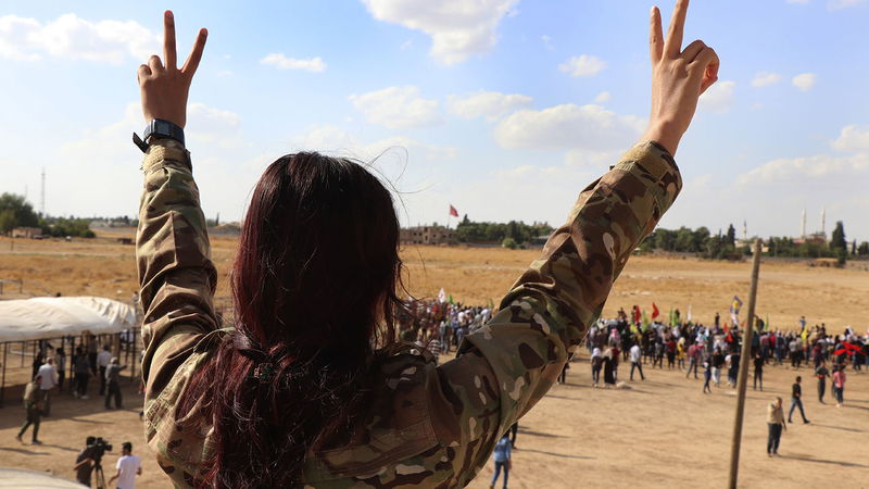 En medlem i Rojavas militär SDF visar segertecknet i samband med en protest mot en kommande turkisk invasion i oktober 2019. Foto: AP.