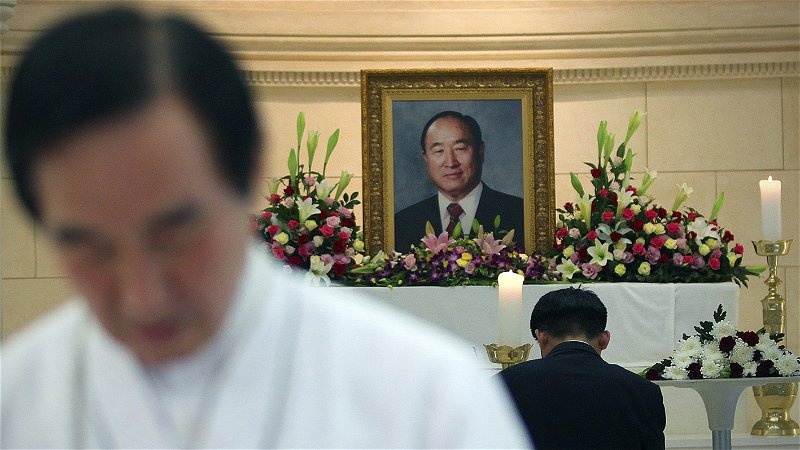 En medlem ber i Enighetskyrkan i Seoul framför ett porträtt av dess grundare Sun Myung Moon den 4 september 2012, strax efter att denne avlidit. Foto: Hye Soo Nah/AP.