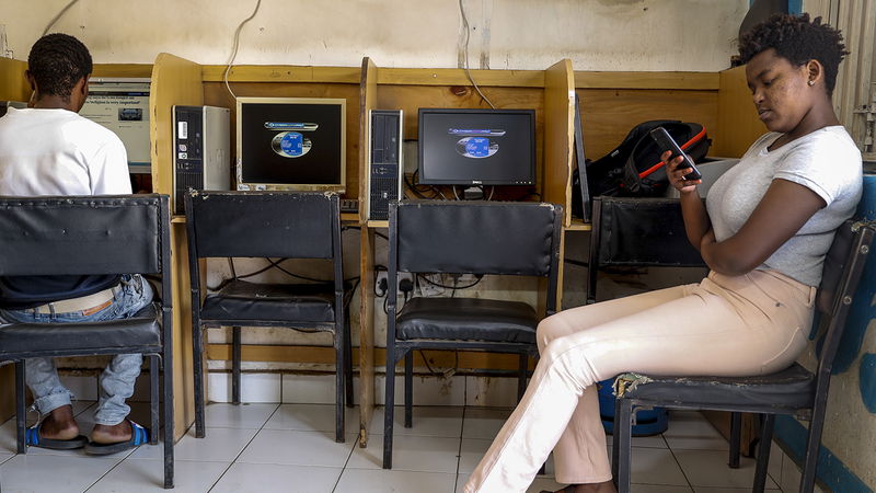 En kund använder wifi på ett internetkafé i det fattiga Kibera-distriktet i Kenyas huvudstad Nairobi 2021. Det enda som behövs för att ta emot direkta pengaöverföringar är en mobiltelefon. Foto: Brian Inganga/AP.