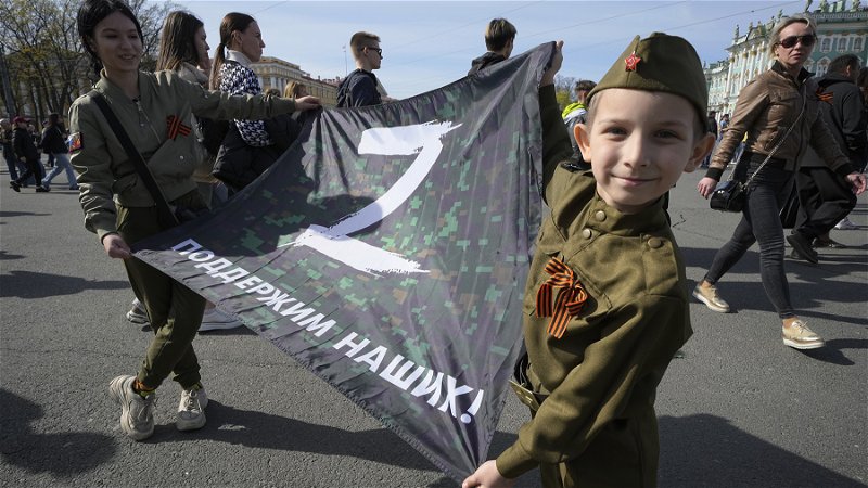 Barn poserar med en flagga med bokstaven Z – symbolen för Rysslands invasion av Ukraina – i Sankt Petersburg på Segerdagen den 9 maj 2022. Foto: Dmitri Lovetsky/AP.