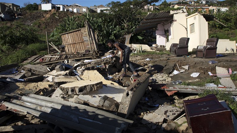 Alwande Ndlovu letar igenom resterna av en grannes hus, som sveptes bort i en översvämning i Umgabada nära Durban i Sydafrika. Foto: AP. 