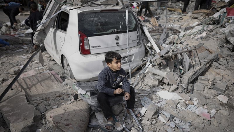 En palestinsk pojke sitter utanför sitt förstörda hem i Kahn Younis i Gazaremsan den 12 januari. Foto: Mohammed Dahman/AP.