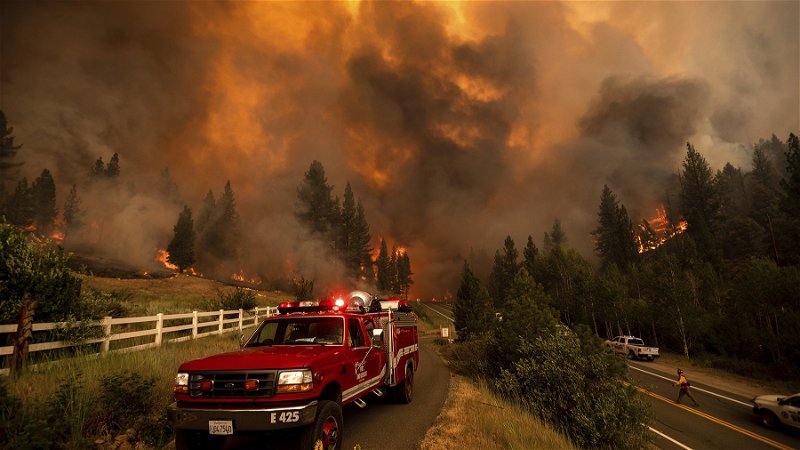 Ett eldmoln syns över ett bostadshus i Markleeville, Kalifornien den 16 juli 2021. Området är ett av flera i USA som försäkringsbolag har börjat dra sig tillbaka från. Foto: Noah Berger/AP.