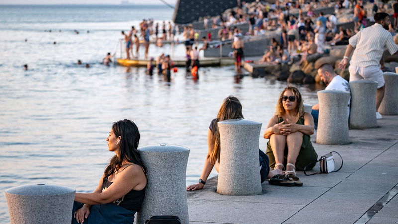 Människor umgås och badar i värmen vid Sundspromenaden i Malmö. Foto: Johan Nilsson / TT.