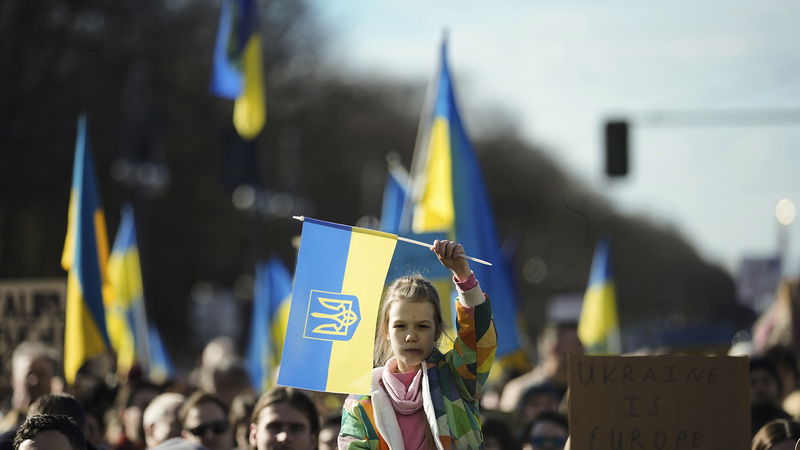 Människor håller en ukrainsk flagga under en demonstration utanför Europaparlamentet i Bryssel. Rysslands krig mot Ukraina har delat den europeiska vänstern och bidragit till den nya partibildningen. Foto: Markus Schreiber/AP.