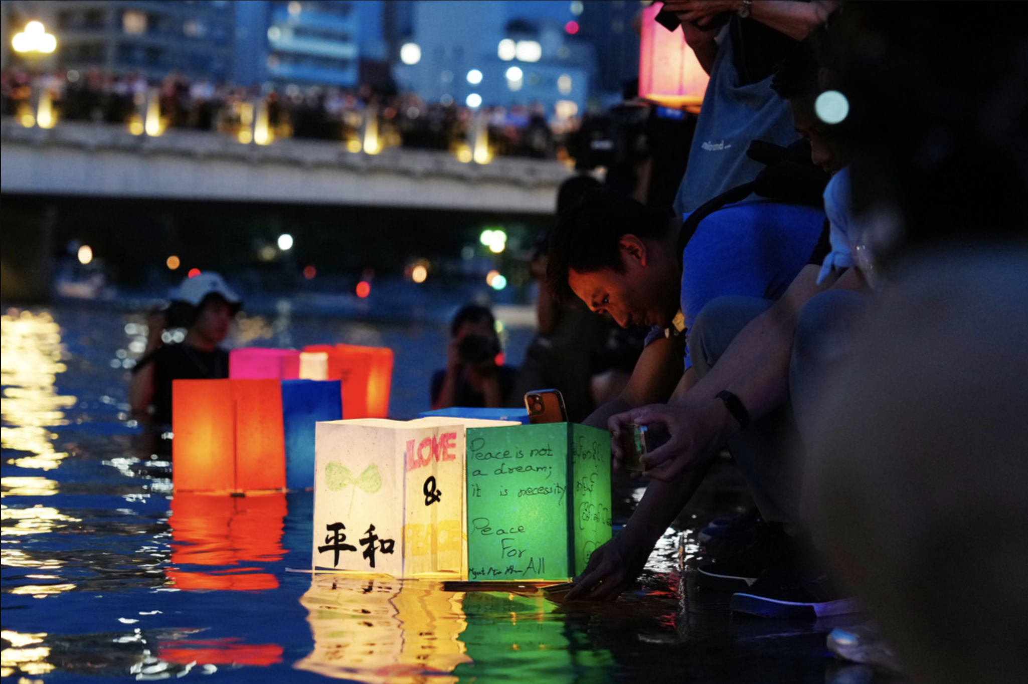 People place paper lanterns on a river at Hiroshima Peace Memorial Park in Hiroshima, Japan, on Aug. 6, 2025.