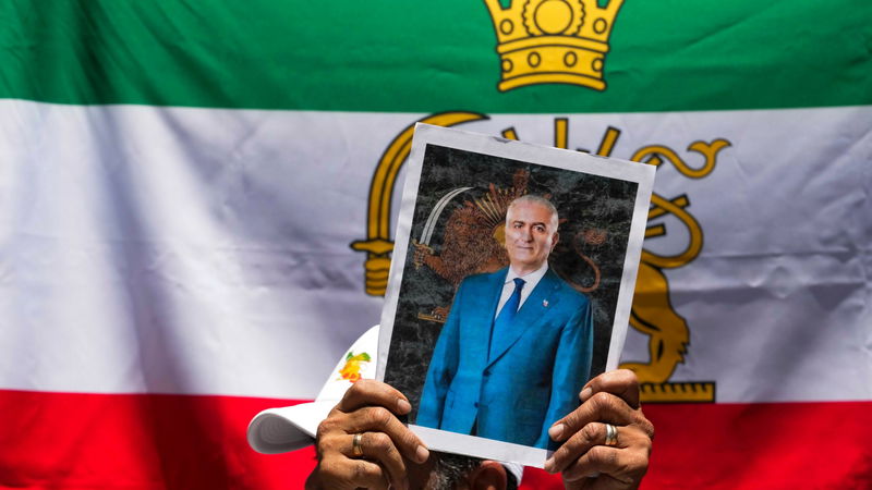 En exiliransk demonstrant i Chile håller upp ett porträtt på Reza Pahlavi, sonen till Irans sista shah. Foto: Esteban Felix/AP/TT.