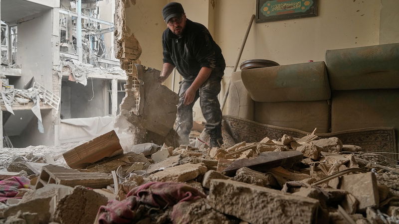 En man rensar bråte i sin förstörda lägenhet efter att en närliggande polisstation blivit träffad av amerikanska och israeliska bomber i mars 2026. Foto: Vahid Salemi /AP/TT