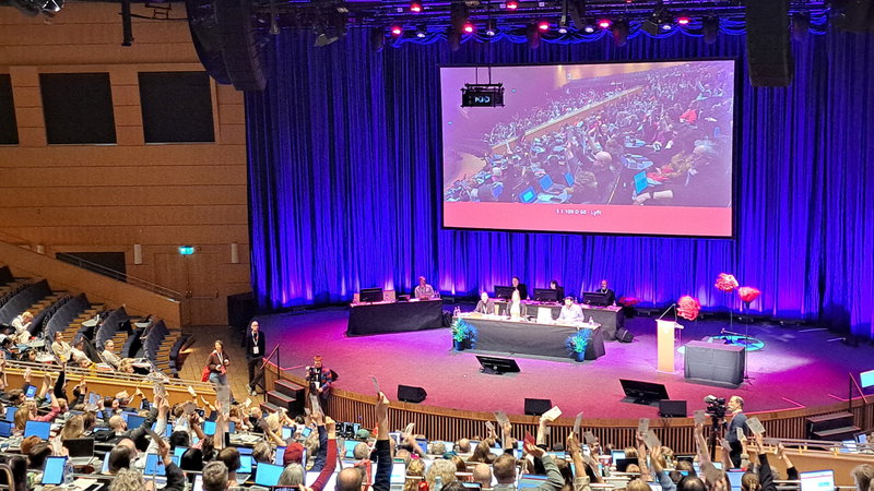 Medlemmar sträcker upp sina röstkort till stöd för motionen om att bevara partiskatten på dagens nivå. Foto: Jacob Lundberg / Flamman.