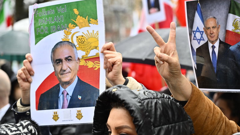 Plakat på Reza Pahlavi och Benjamin Netanyahu hålls upp av demonstranter i Stockholm, mars 2026. Foto: Anders Wiklund/TT