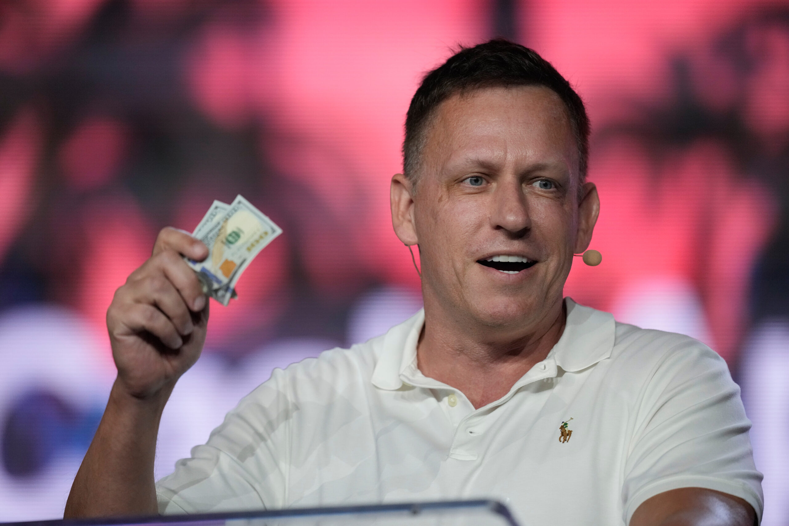 Foto: Rebecca Blackwell/AP Peter Thiel, en av Palantirs grundare, viftar dollarsedlar på Bitcoin-konferens i Miami.