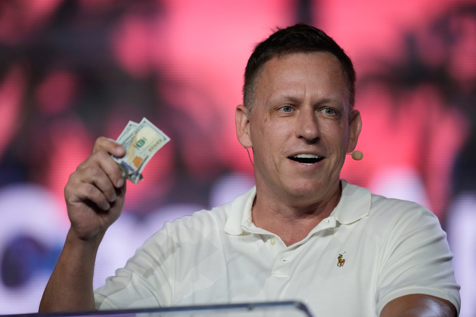 Foto: Rebecca Blackwell/AP Peter Thiel, en av Palantirs grundare, viftar dollarsedlar på Bitcoin-konferens i Miami.